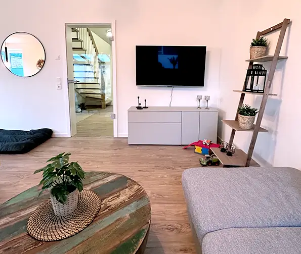 Wohnzimmer mit Fernseher, Spieleecke und Hundedecke