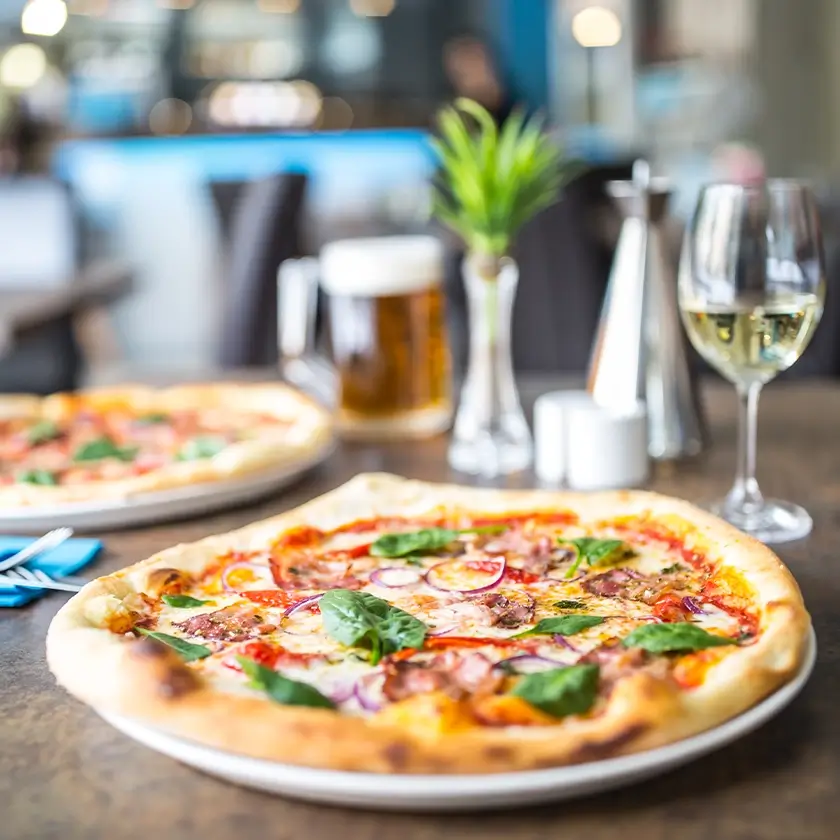 Pizza auf einem Teller mit einem Glas Wein und einem Glas Bier
