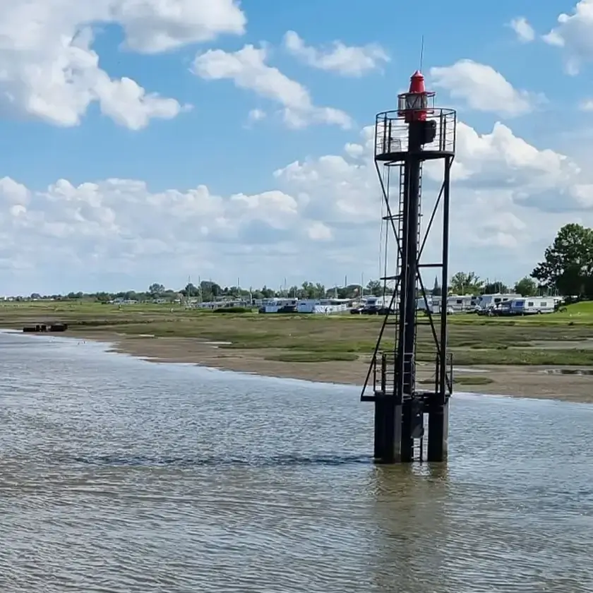 Wasser und Strand, im Hintergrund Campingplatz
