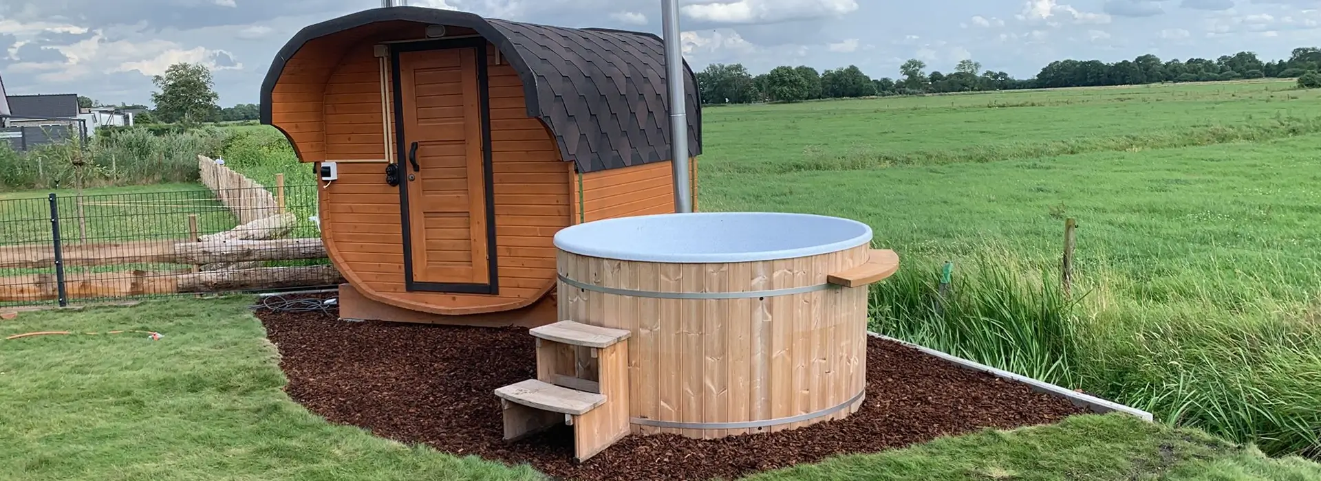 Abgedecktes Hotfass neben einer Gartensauna