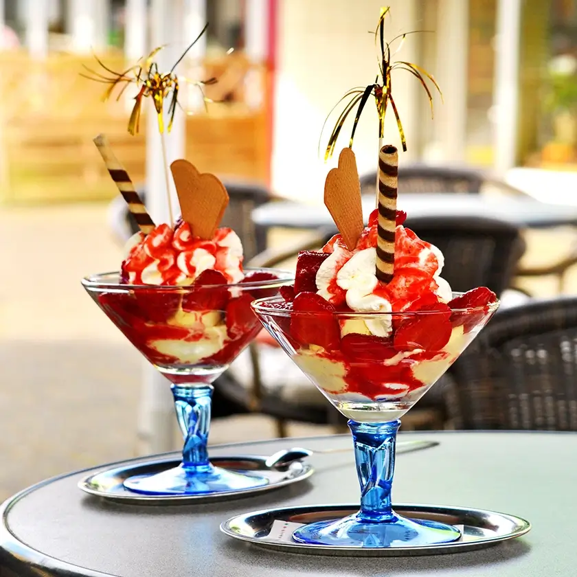2 Eisbecher mit Fähnchen und Waffel auf einem Tisch