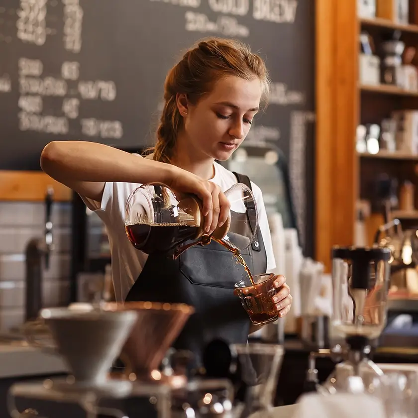 Frau Barösta bereitet einen Kaffee zu