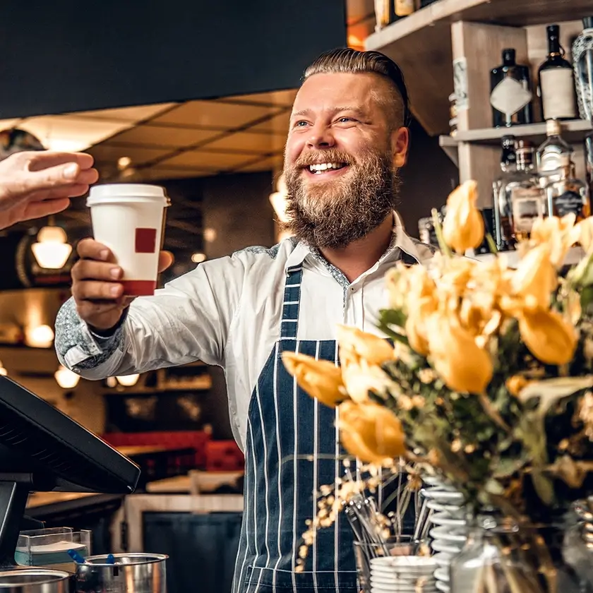 Verkäufer reicht Kunden Kaffee to go über den Tresen